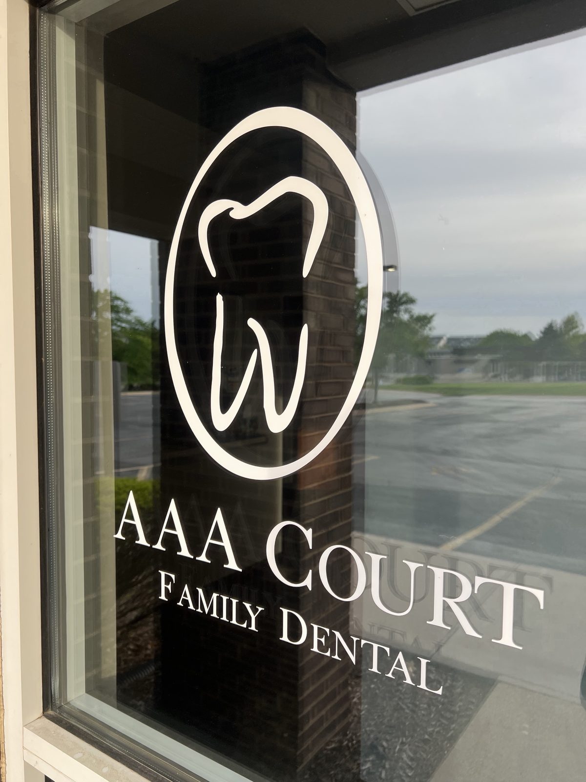 The AAA Court Family Dental entrance, vinyl tooth logo etched on the glass front door in Bettendorf, Iowa